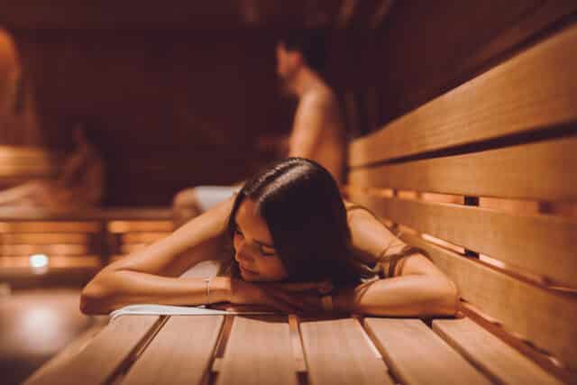 Junge Frau liegt in der gemischten Sauna der Therme Wien