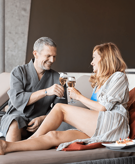 Mann und Frau stossen mit Sekt oder Champagner an waehrend des Relax Tagesurlaubs