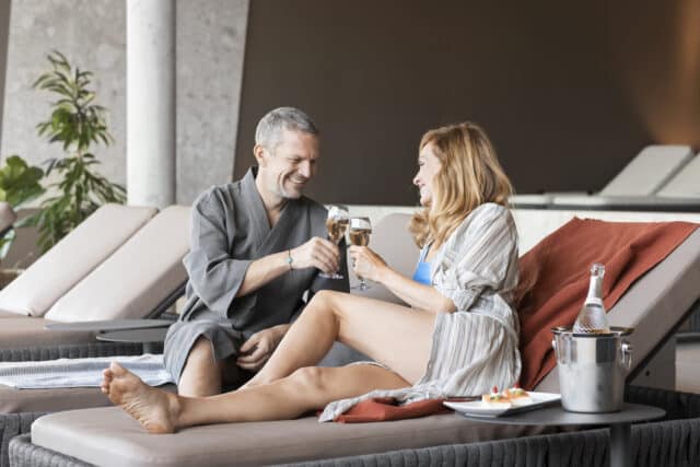 Paar stoesst mit Champagner an in der Relax Lounge der Therme Wien.