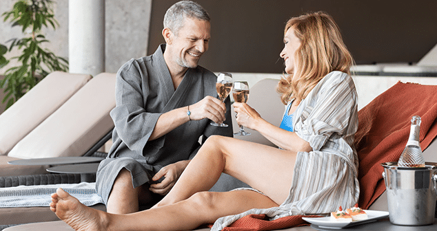 Mann und Frau stoessen mit Sekt oder Champagner an waehrend des Relax Tagesurlaubs