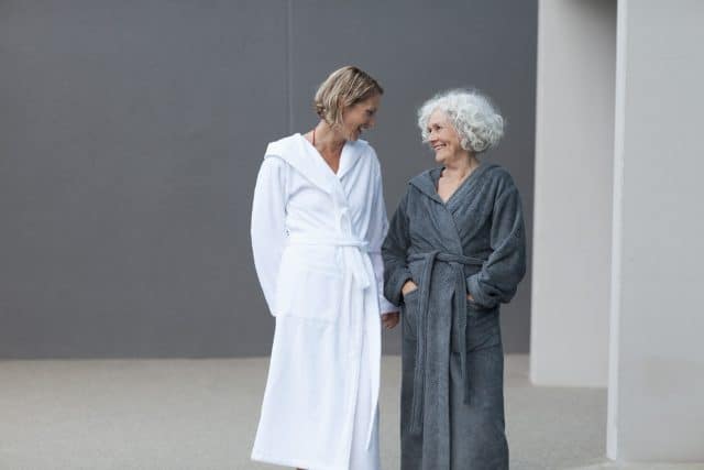 Zwei Frauen im Bademantel stehen in der Therme Wien. Eine ist eine juengere Frau, eine ist etwas aelter. Vermutlich Mutter und Tochter.